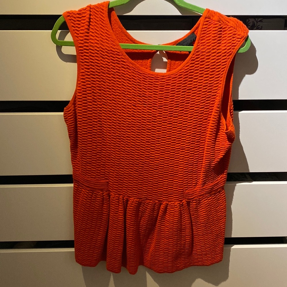 The orange sleeveless top with a peplum finish on the bottom and keyhole bac